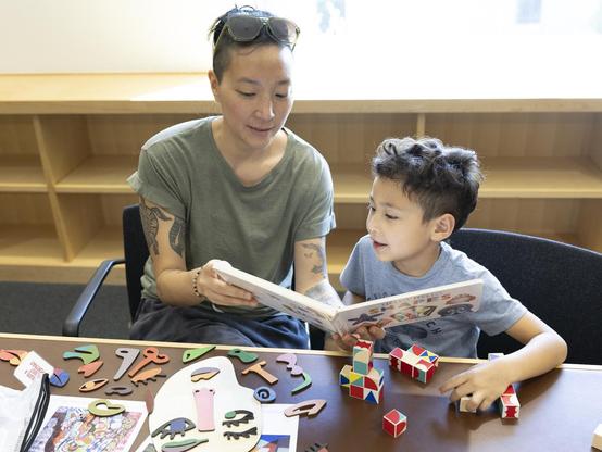 A woman and her pre-K-aged son read a book from one of the Georgia Museum of Art’s “Museum in a Box” kits. In front of them are various hands-on activities, also from the box.