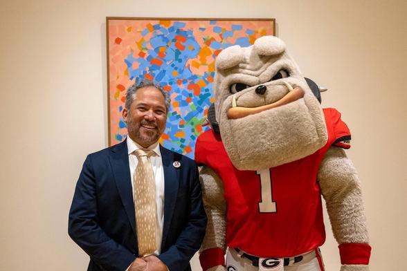 Georgia Museum of Art director David Odo standing next to University of Georgia mascot Hairy Dawg (a man in a bulldog costume) in front of a Carl Holty painting in the galleries.