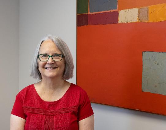 Paula Arscott smiles next to a painting.