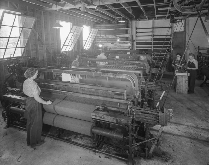 A large room with several weaving devices which are outputting nice looking blankets.